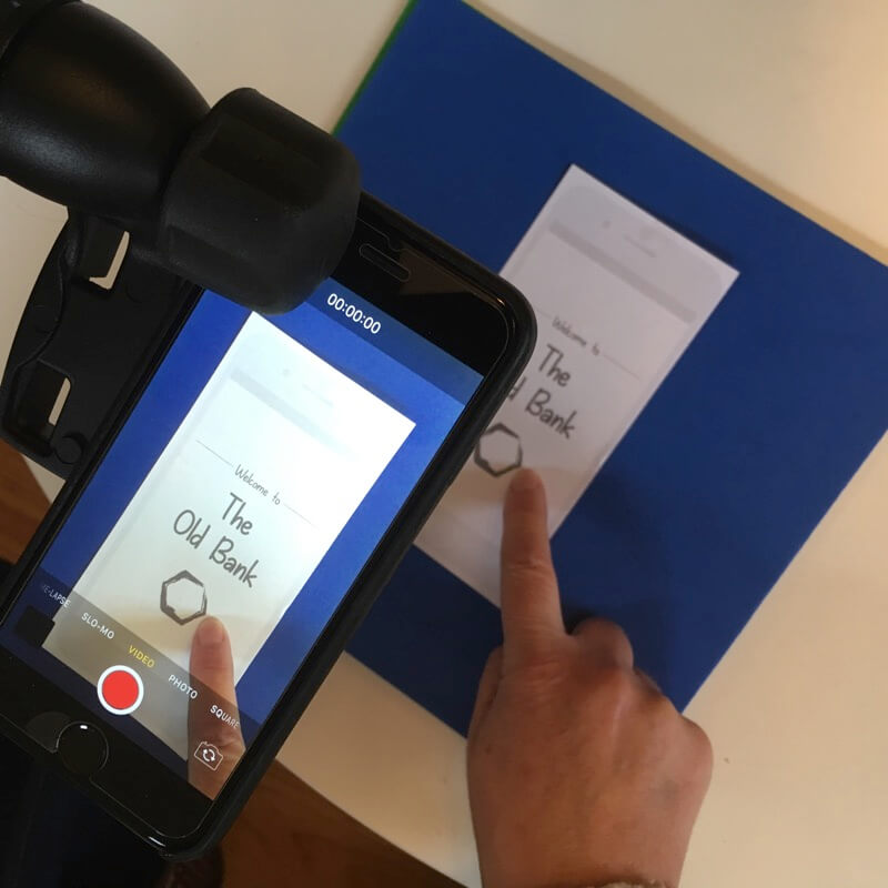 a phone on a tripod looking down on a paper prototype laid on a desk